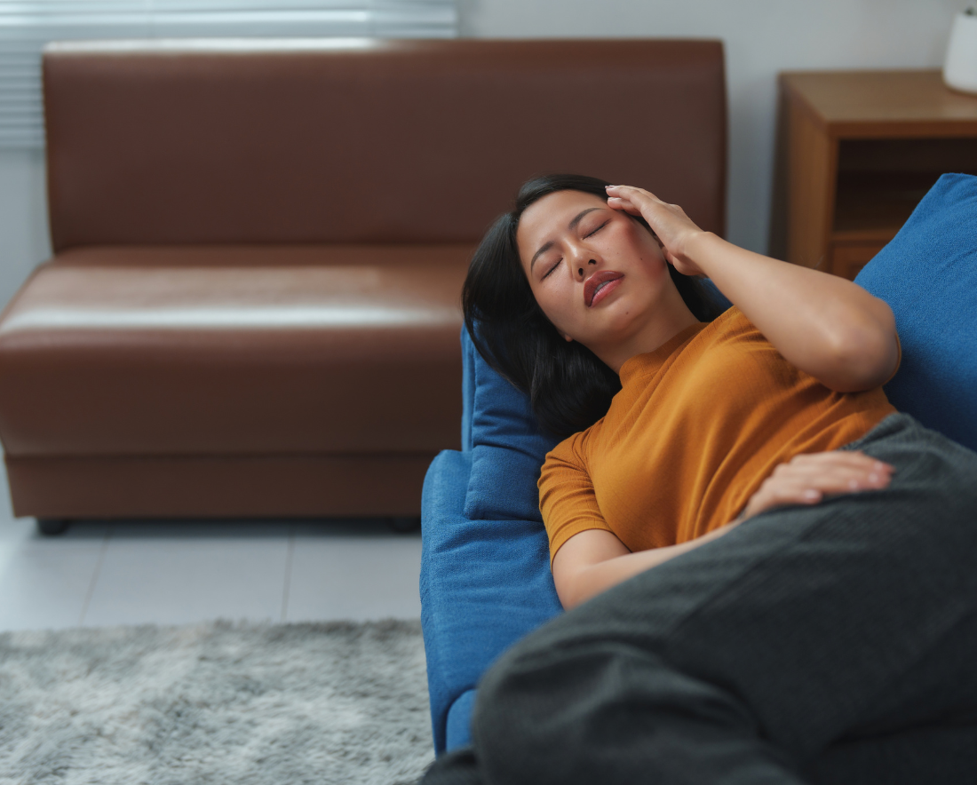 A woman feeling dizzy and lying down on a couch in the Cayman Islands.