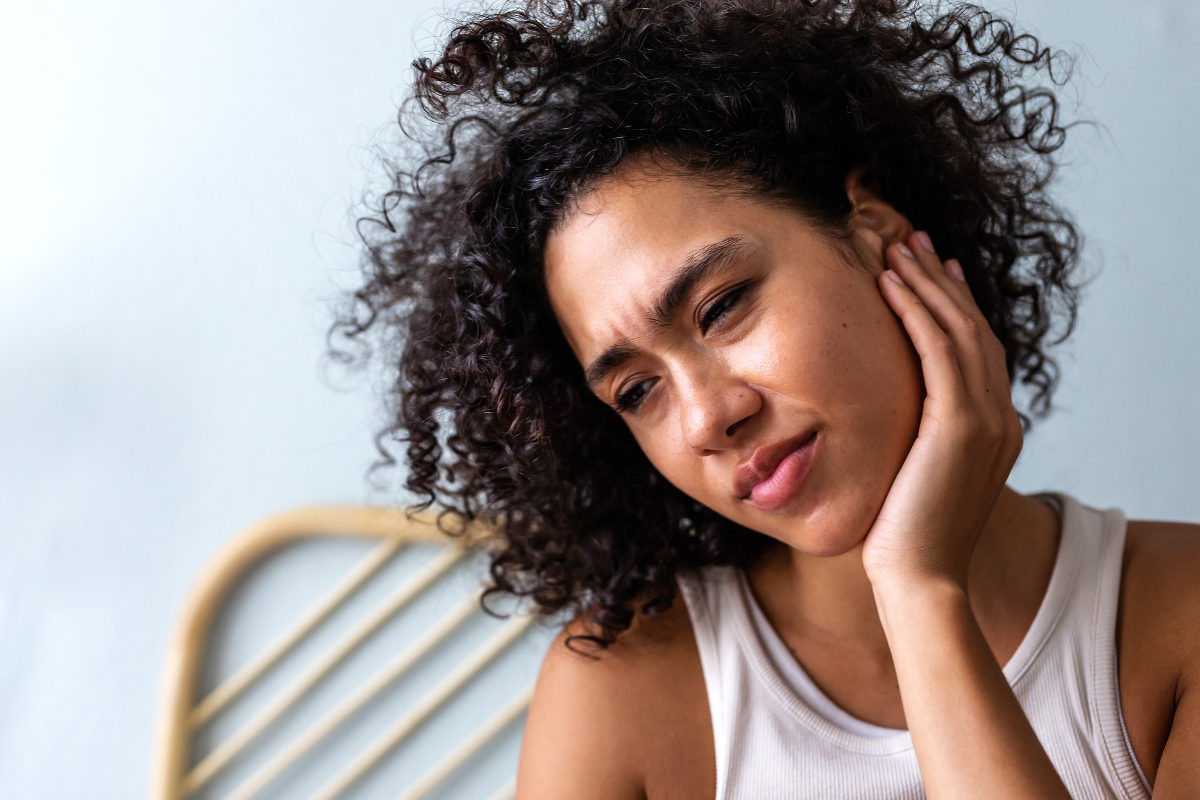 A woman experiencing TMJ pain.